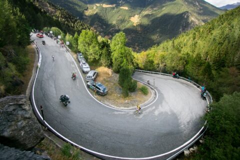 Wide shot of a cyclist rounding a paved mountain switchback