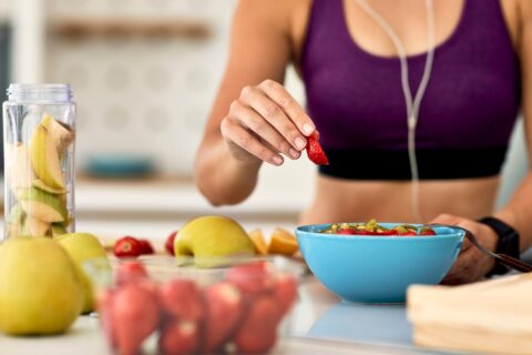 An athletic woman prepares a bowl of fruit.