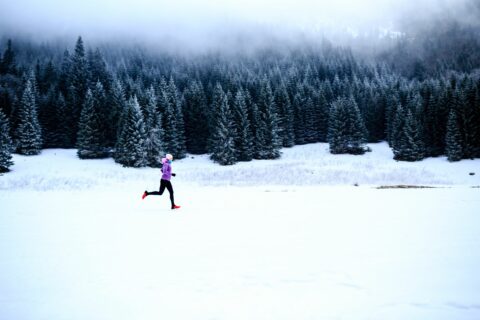 Woman running through the snow on a foggy day