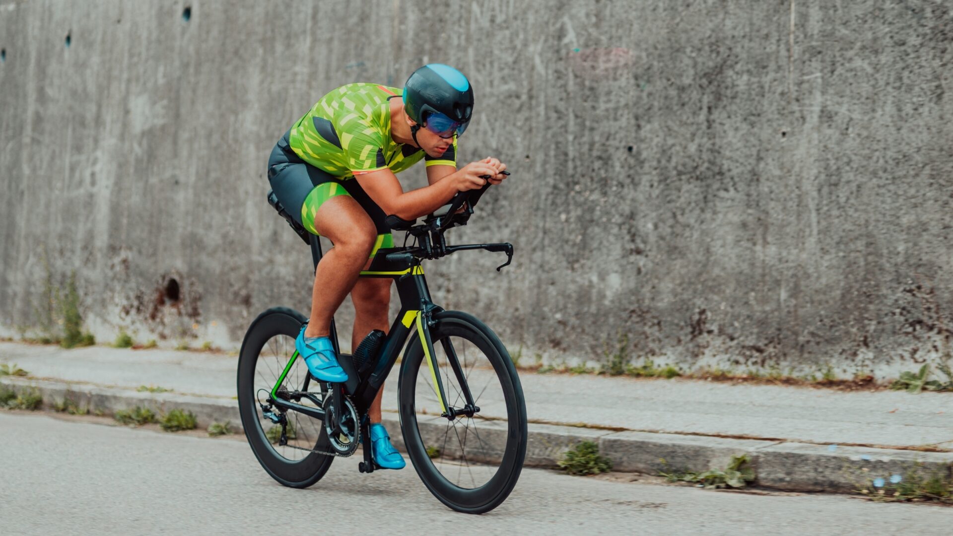 A triathlete rides past a concrete wall