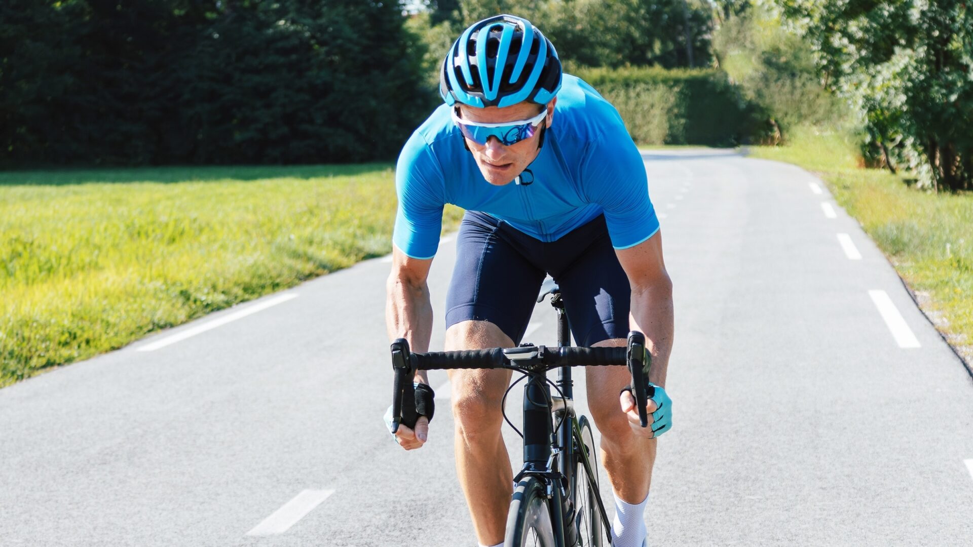 Cyclist riding down a road on a sunny day