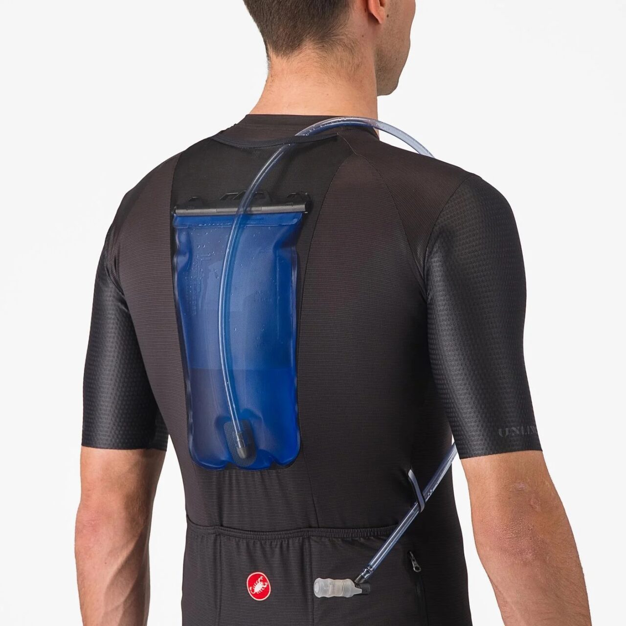 Rear view of a man in a cycling jersey with a hydration bladder visible in a mesh pocket in the middle of the back.