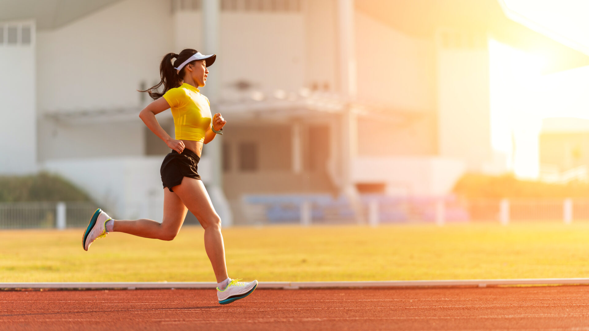 Woman running on sunlit track.