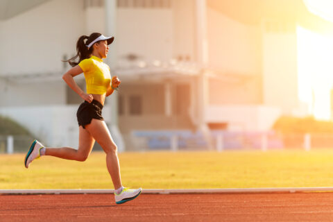 Woman running on sunlit track.