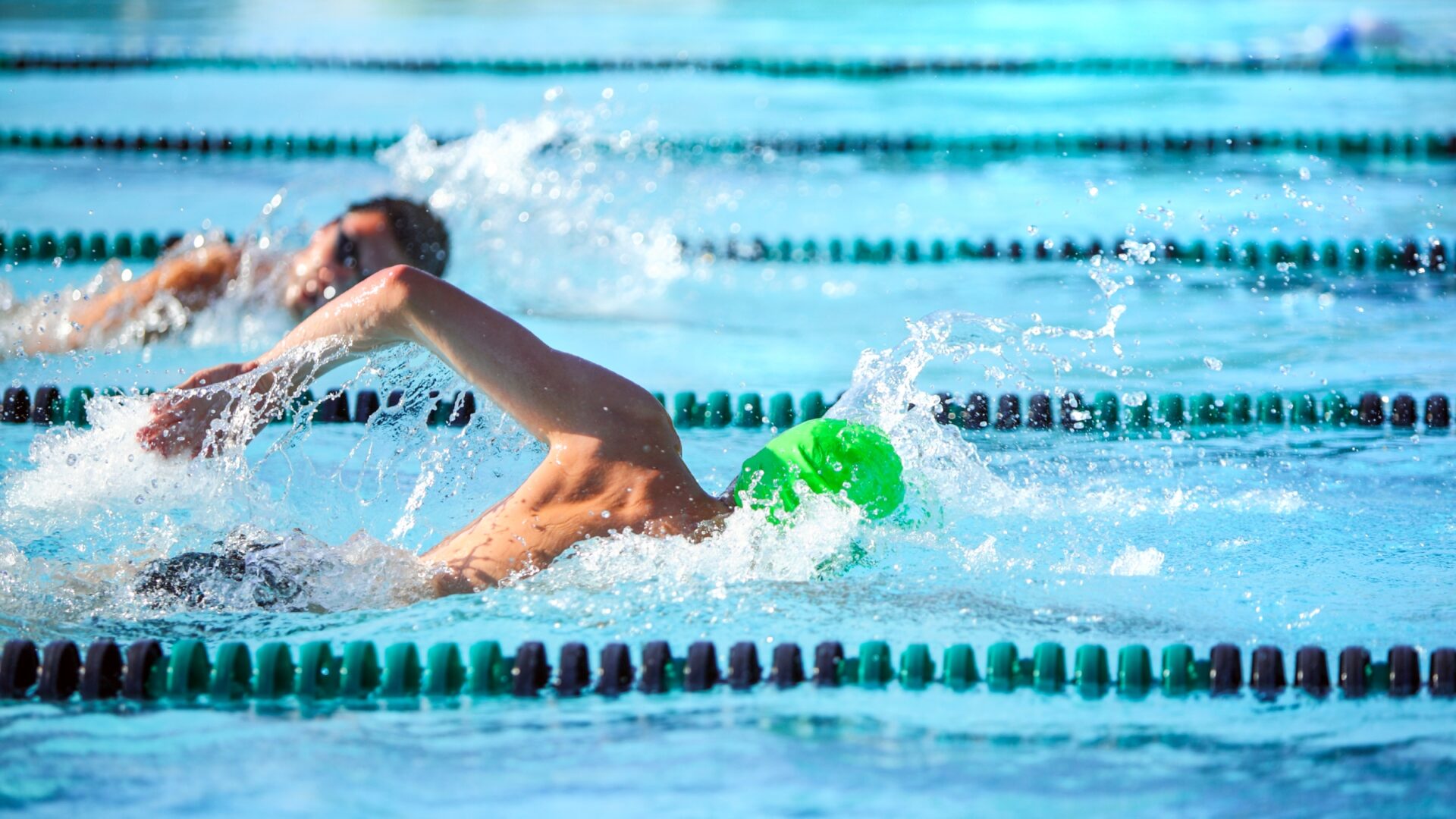 Two men swimming in lap lanes of an outdoor pool