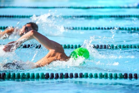 Two men swimming in lap lanes of an outdoor pool