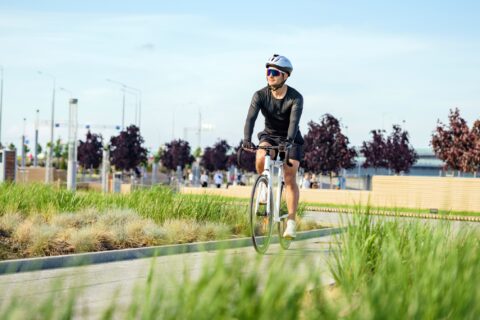 Male cyclist rides through a public park on a sunny day