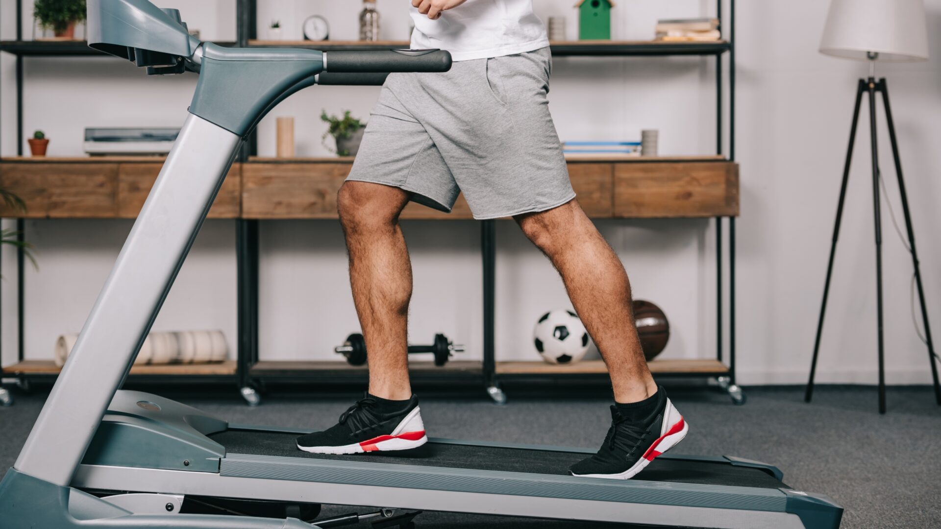 Lower shot of a man running on an incline treadmill in his home