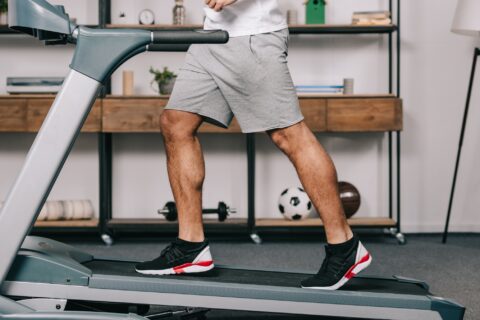 Lower shot of a man running on an incline treadmill in his home