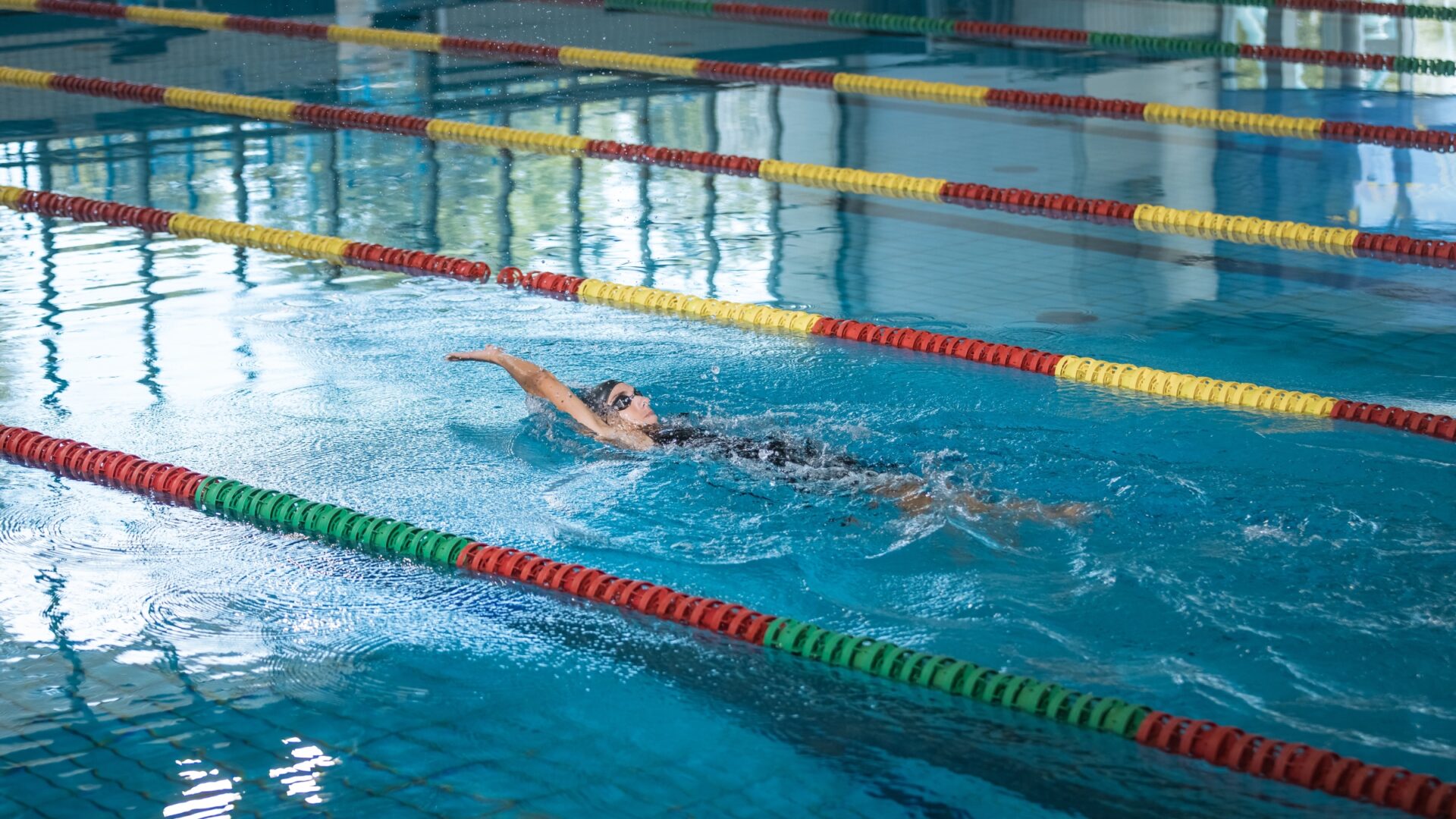 Woman swimming backstroke in an indoor pool