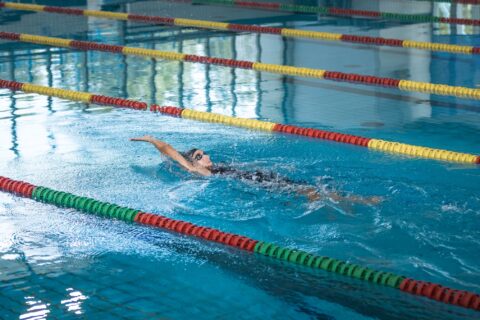 Woman swimming backstroke in an indoor pool